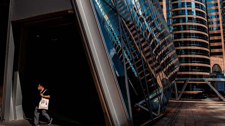 Man wearing mask and walking besides the real estate office building