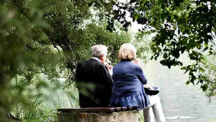 Two elderly people sitting on a bench