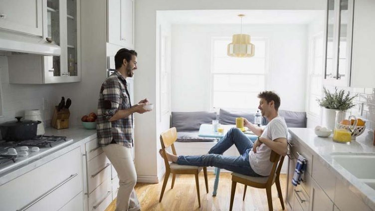 Two friends talking while having breakfast in the kitchen area