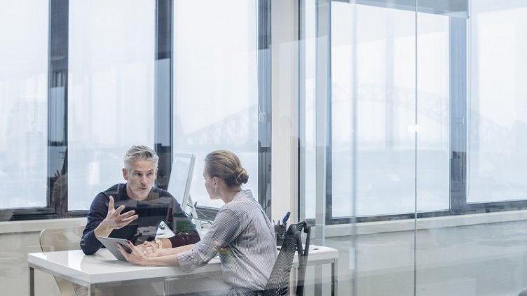 one male and female employee sitting in office cabing and discussing