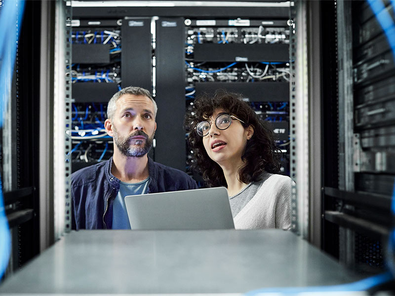 A man and a woman inspecting racks in a data center.