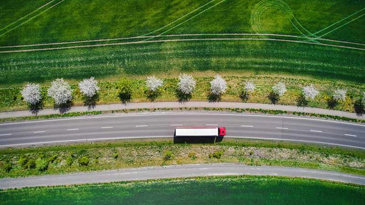 Drone shot direct above a truck moves along a single road.