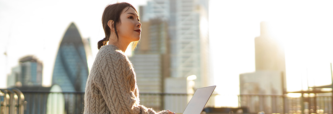 Young woman with laptop working on roof terrace