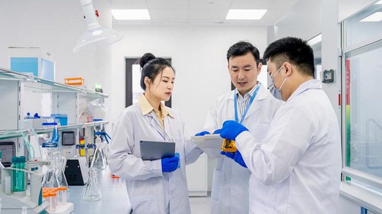 Scientists discussing the results of the experiment in laboratory holding a vial with glassware