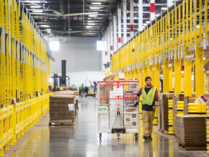 Ouvrier logistique déplaçant le chariot à cartouches dans l'entrepôt