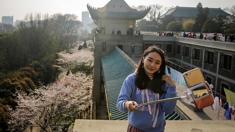 A tourist is taking her selfie using a selfie stick
