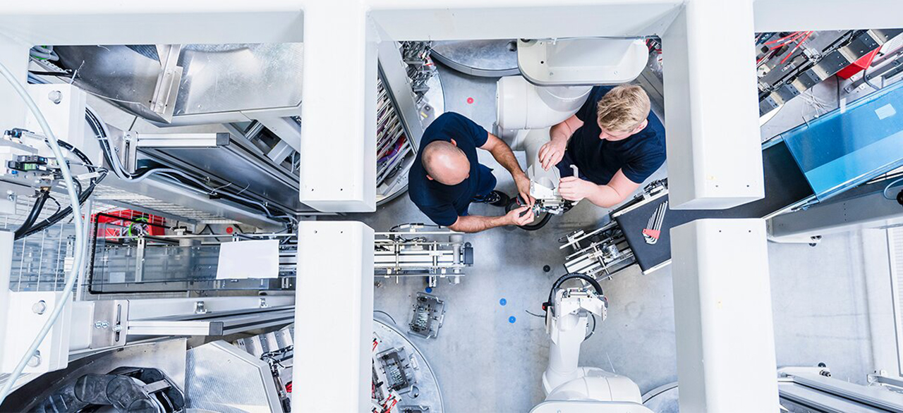 Top view of two colleagues working at industrial robot
